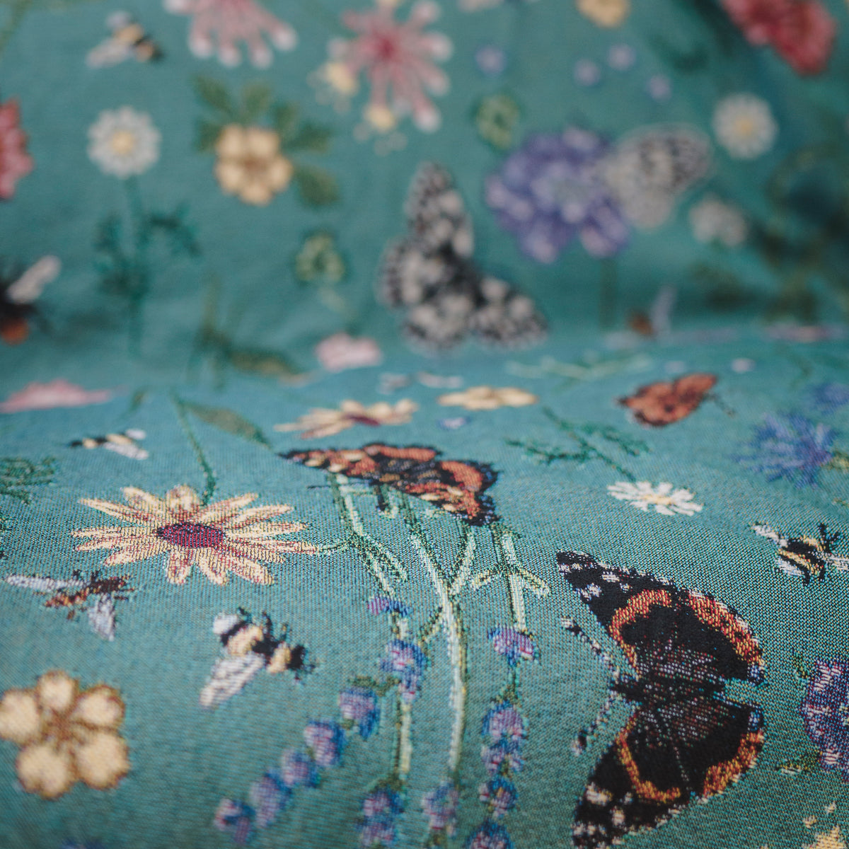 woven throw in teal with butterflies and flowers, thrown over sofa