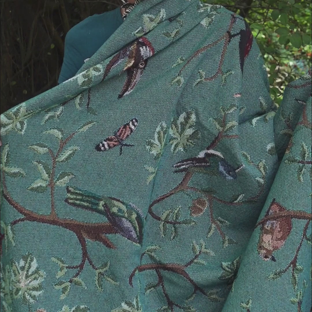 video showing tropical bird blanket with dark green front and light purple reverse
