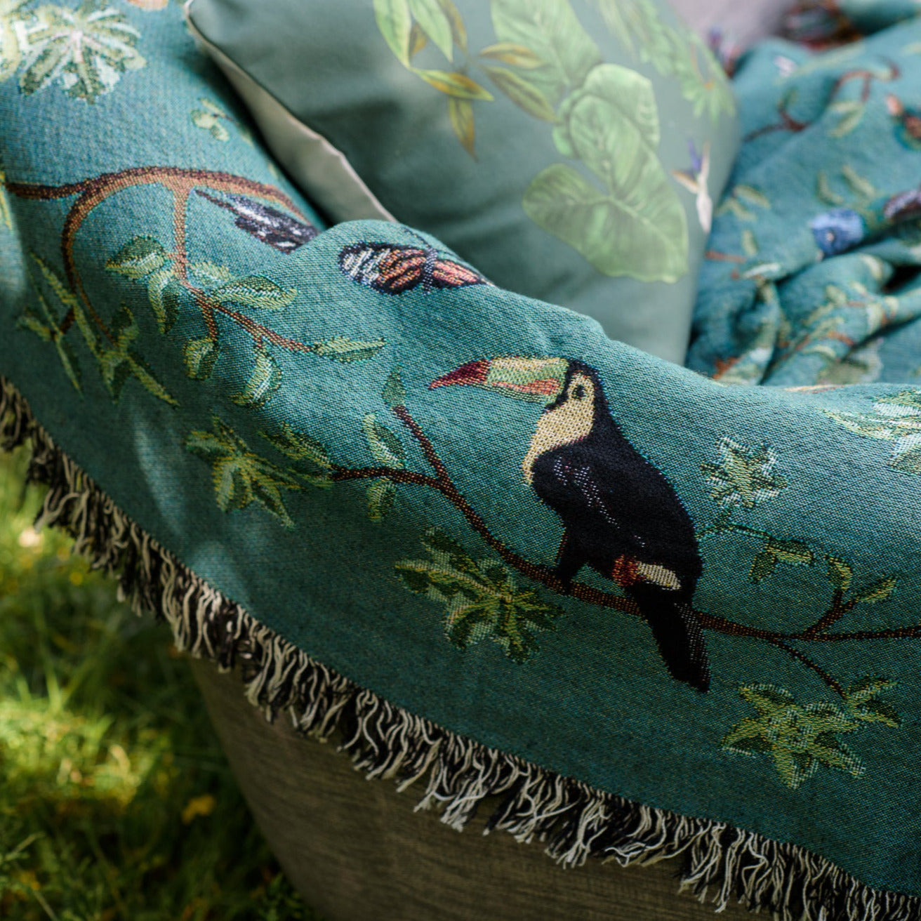 detail of woven blanket with fringe, showing tropical birds and a toucan