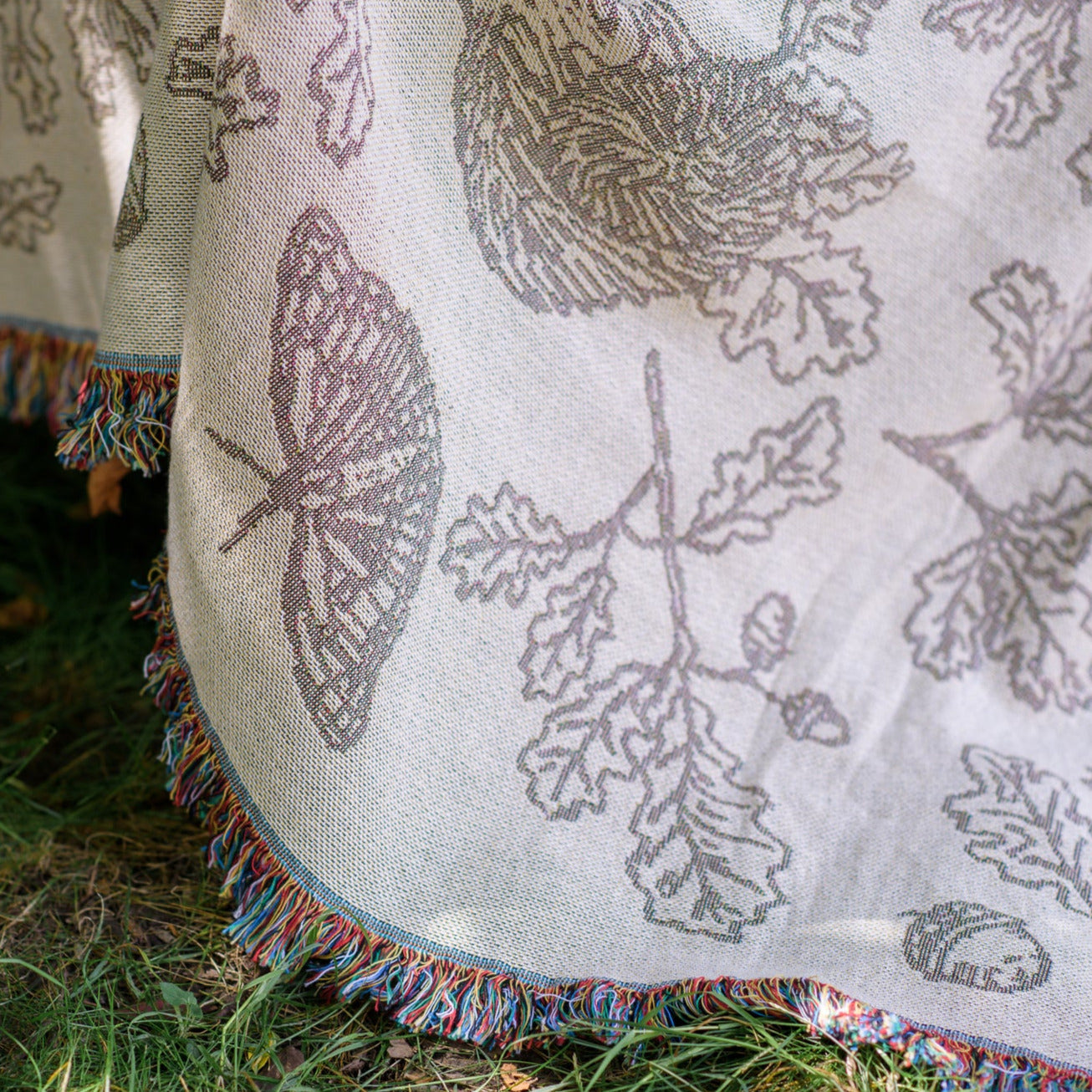detail of cream two tone woven blanket featuring oak woodland butterfies and birds