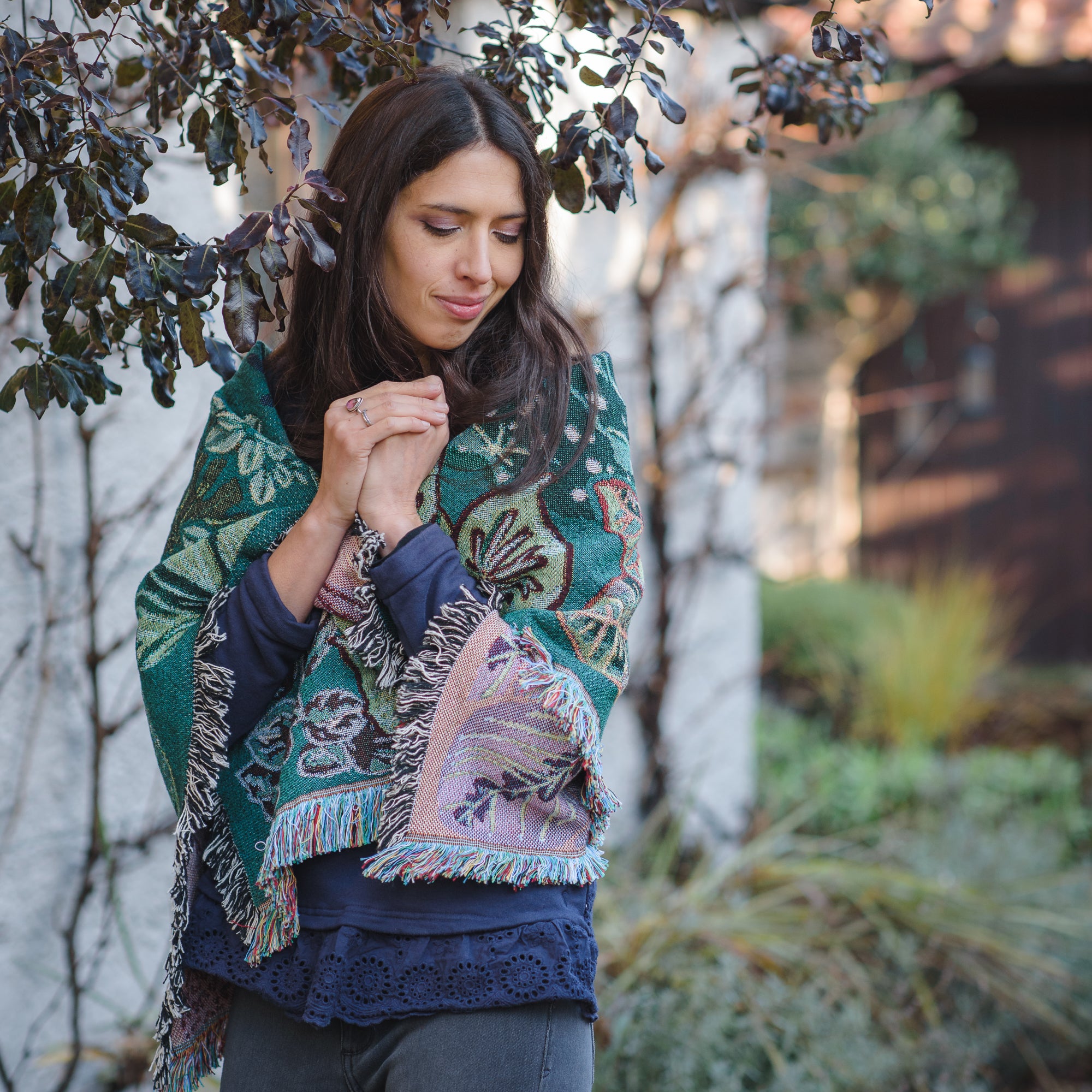 woven wrap blanket with fringe wrapped around womans shoulders in winter garden