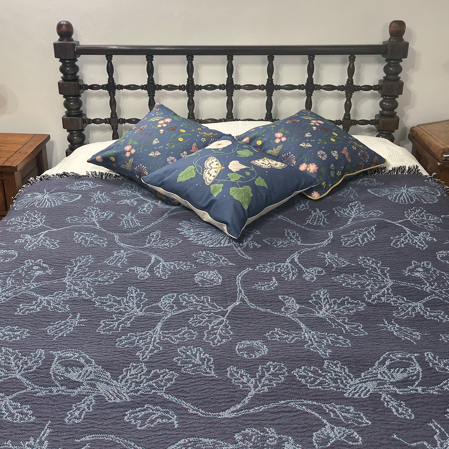 blue two tone woven blanket featuring oak woodland butterfies and birds spread across a bed