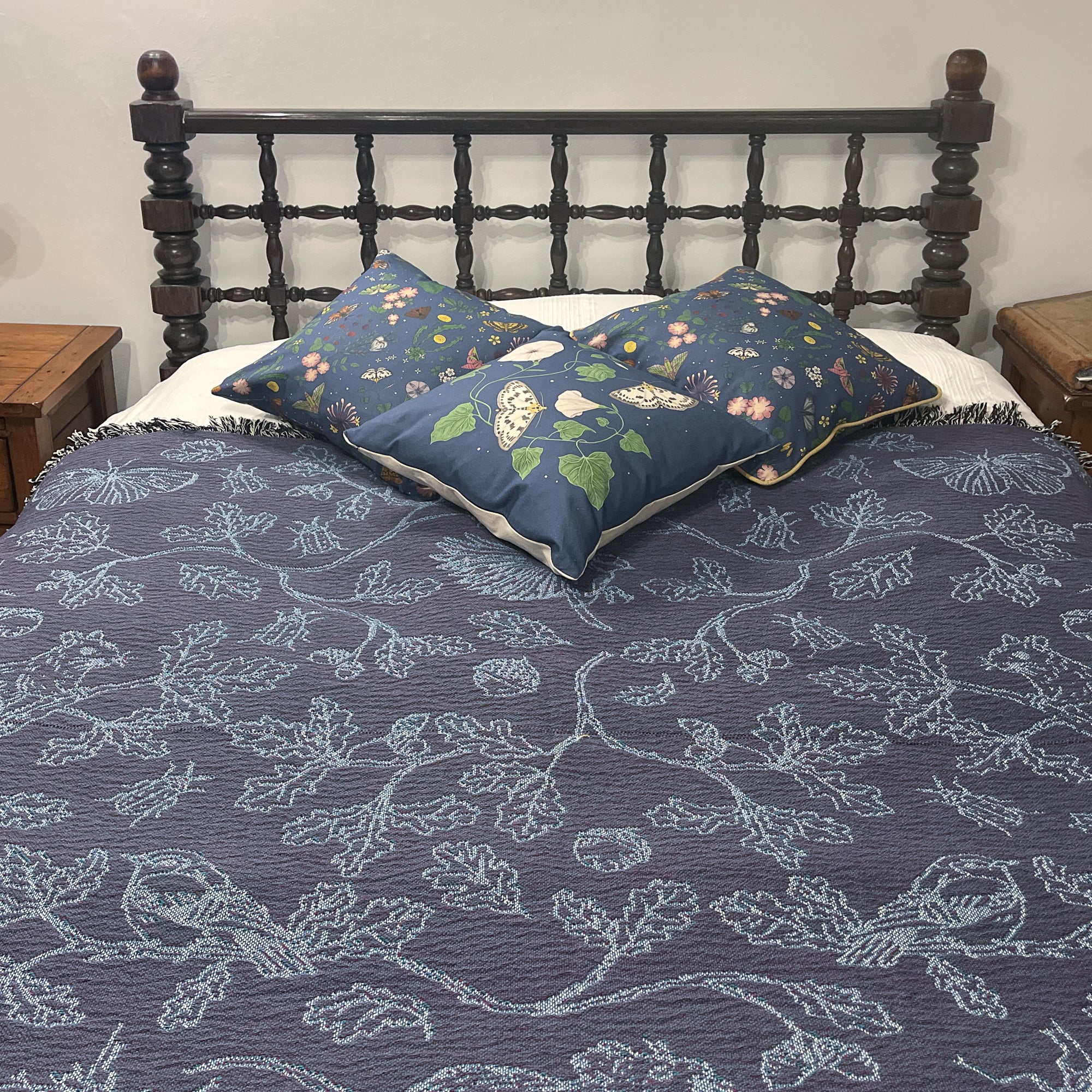 blue two tone woven blanket featuring oak woodland butterfies and birds spread across a bed