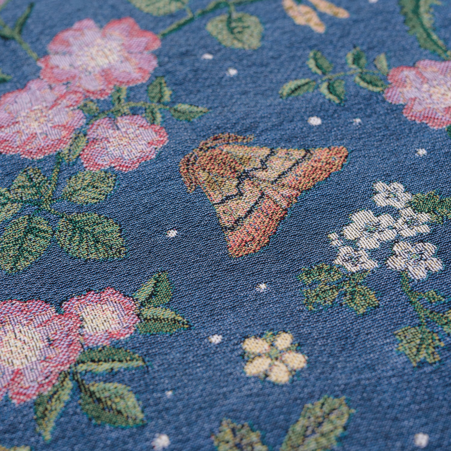 detail of small dark blue woven wrap blanket with delicate moth and flower pattern