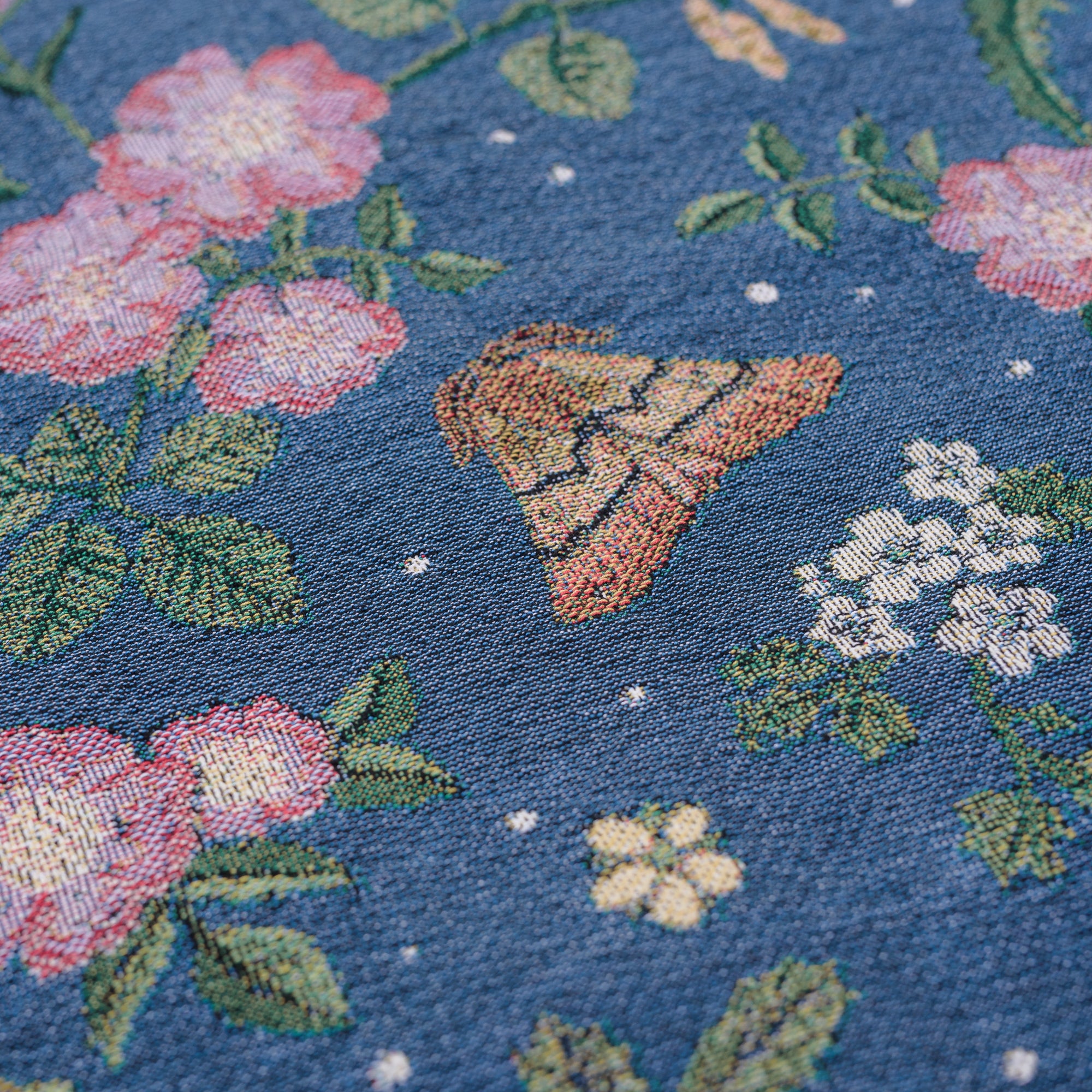 detail of small dark blue woven wrap blanket with delicate moth and flower pattern