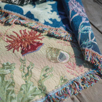 a Arcana Intertidal Sand blanket on a wooden deck, showing woven detail of a beadlet anemone