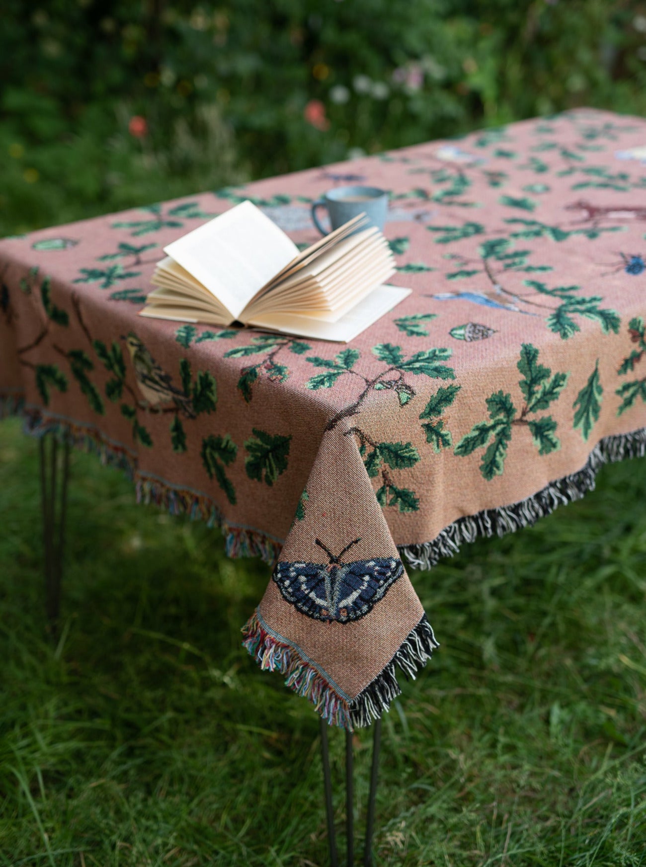 russet coloured woven blanket with teal reverse featuring birds, squirrels and oak, used as table cloth