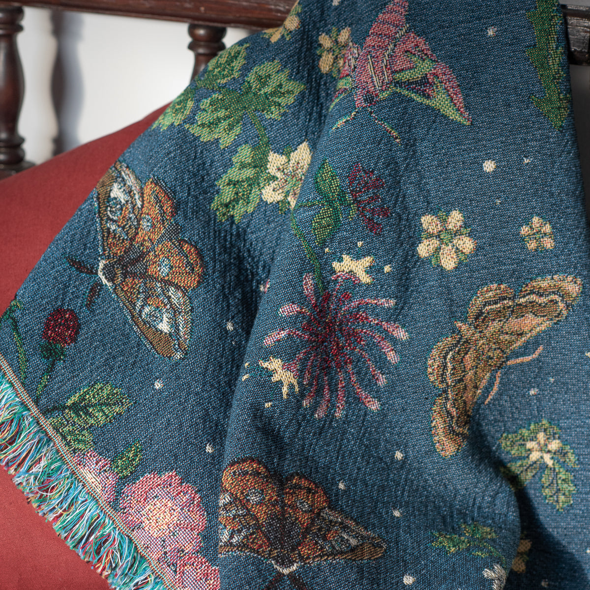 detail of small dark blue woven wrap blanket with delicate moth and flower pattern 