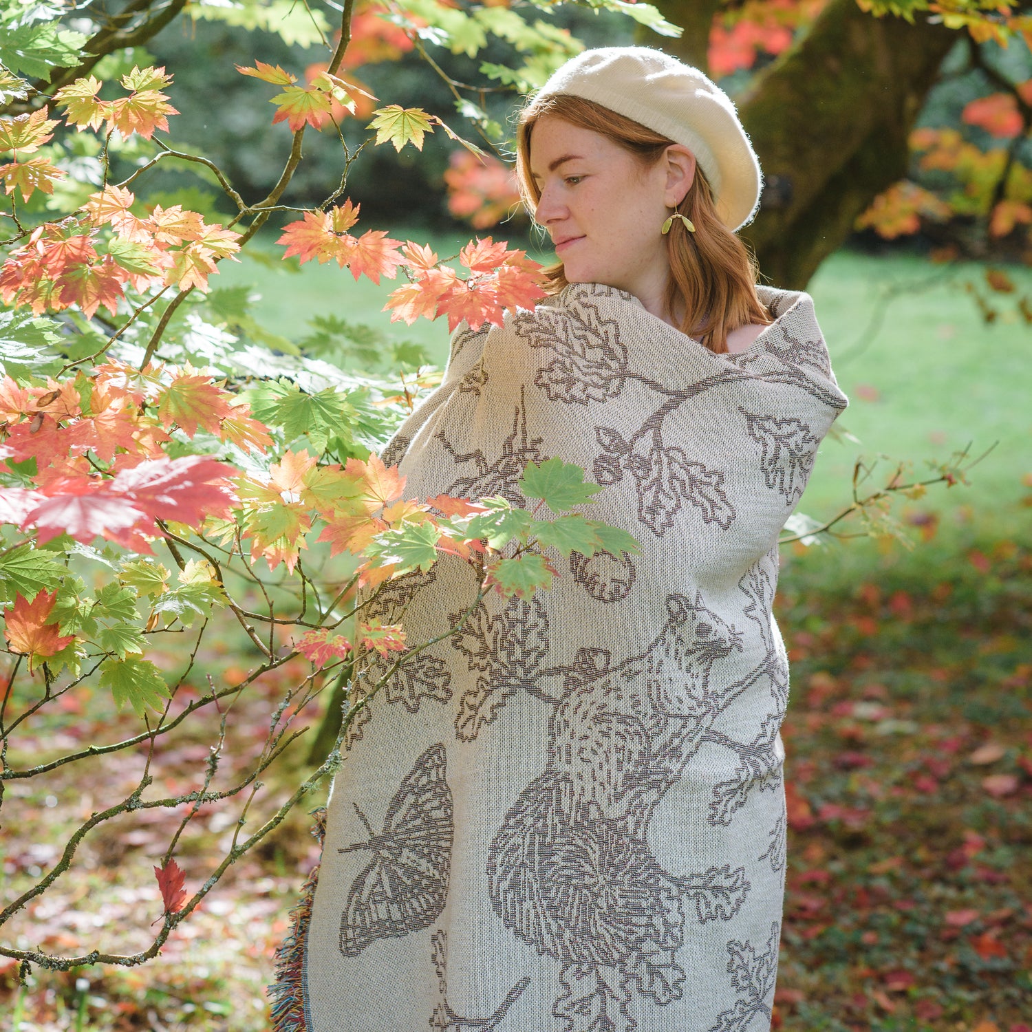 girl wrapped in cream two tone woven blanket featuring oak woodland butterfies and birds