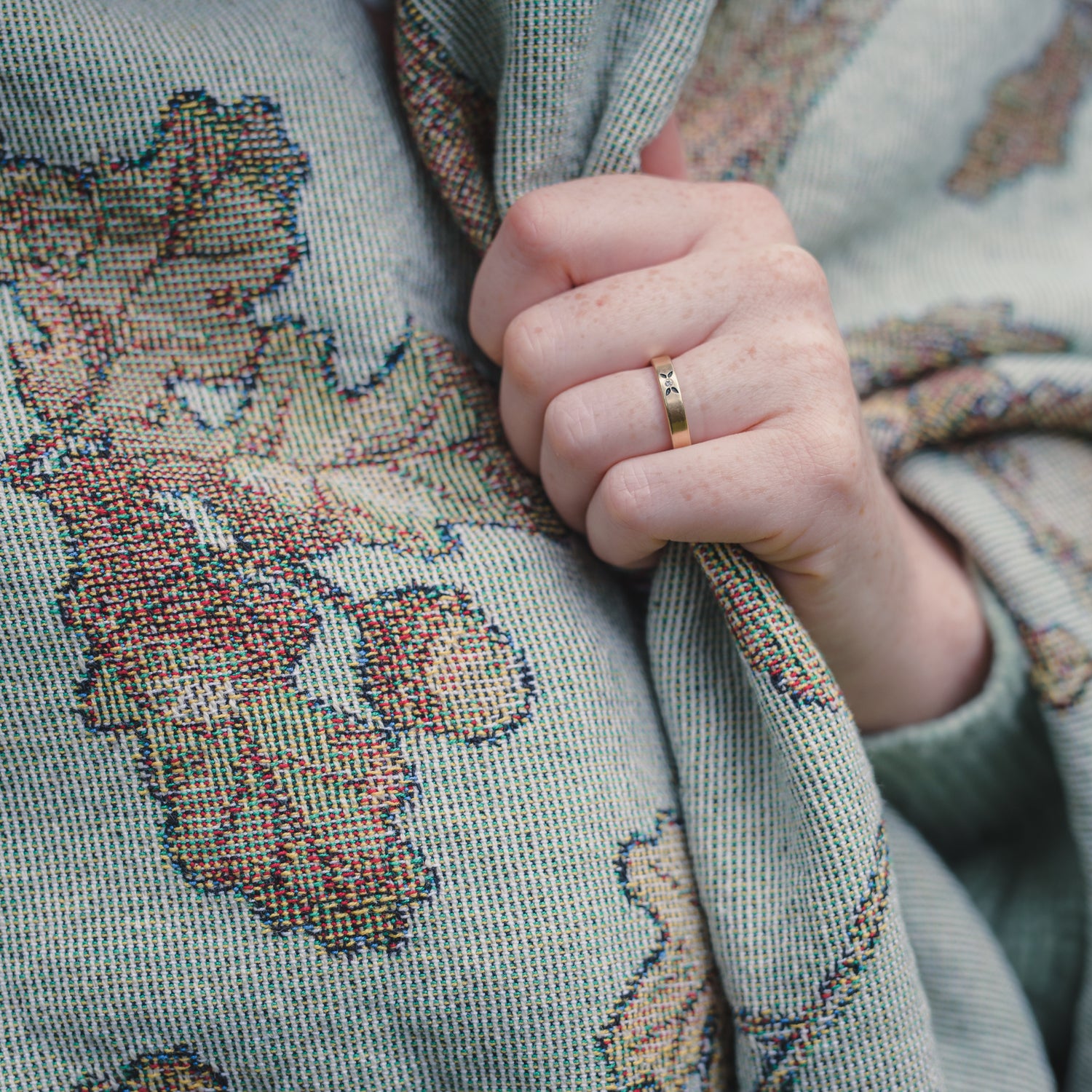 a woman wearing an Arcana Wild Oak Wrap Blanket showing detail of acorns and oak leaves