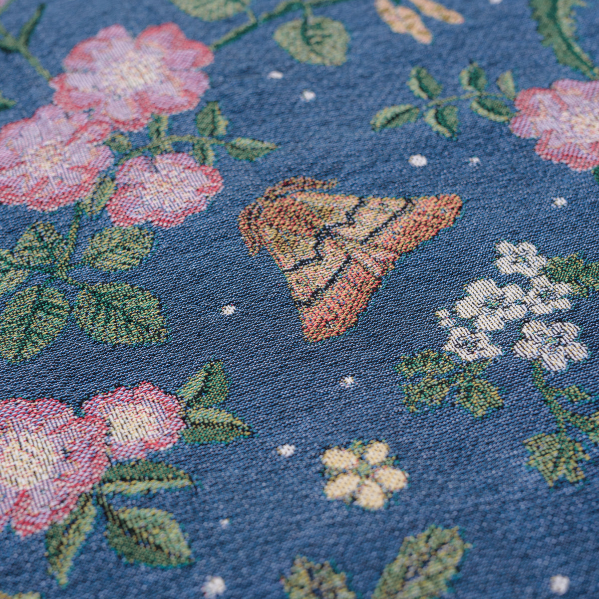 detail of small dark blue woven wrap blanket with delicate moth and flower pattern 